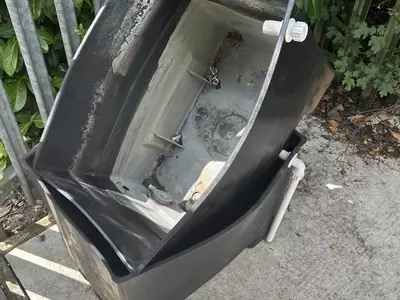 Original plastic inlet water tanks removed from a cold pressure washer system after deforming due to constant hot water feed. The unsealed design also caused condensation buildup inside the cabinet, leading to poor hygiene and reliability issues.
